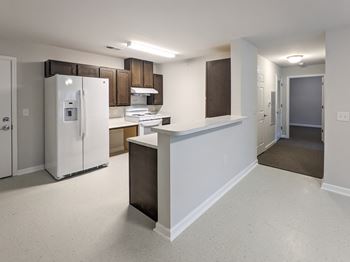 A kitchen with white appliances and brown cabinets. at Bickerstaff Crossing Apartments, Henrico